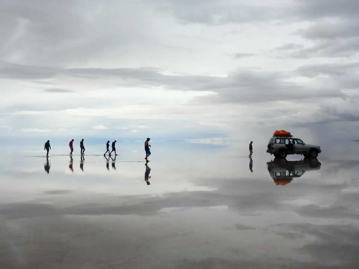 salar de uyuni people and jeeps reflections